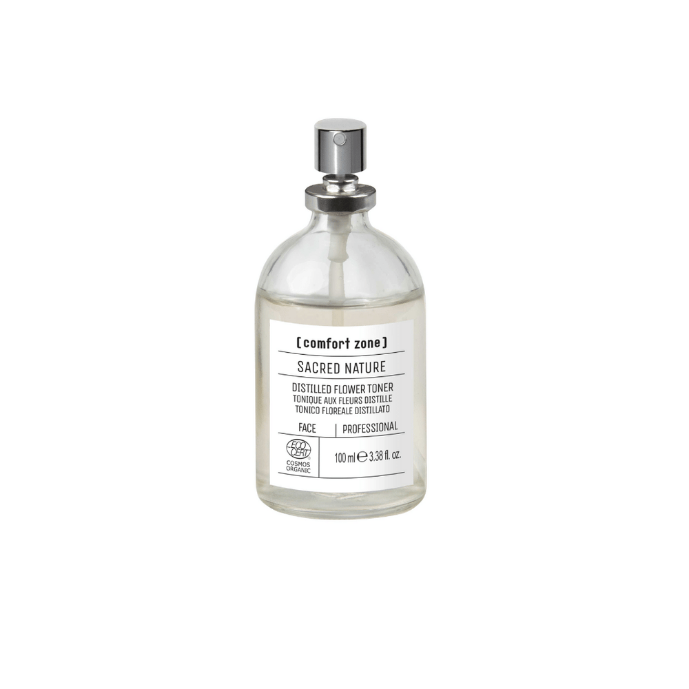 Clear glass spray bottle containing a floral toner with a silver spray nozzle labeled Sacred Nature Distilled Flower Toner Professional | [ comfort zone ] for skincare use