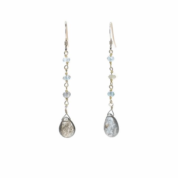 Pair of delicate drop earrings featuring light blue gemstones and teardrop-shaped metallic stones, called Alice Gemstone Earrings | Liv & B.