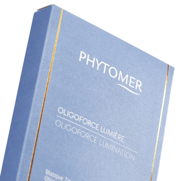 Close-up of a blue and gold-accented package of Oligoforce Lumination Targeted Dark Spot and Wrinkle Sheet Mask With Vitamin B3 - 4 Mask Set| Phytomer, a skincare product designed for targeted dark spot and wrinkle treatment.