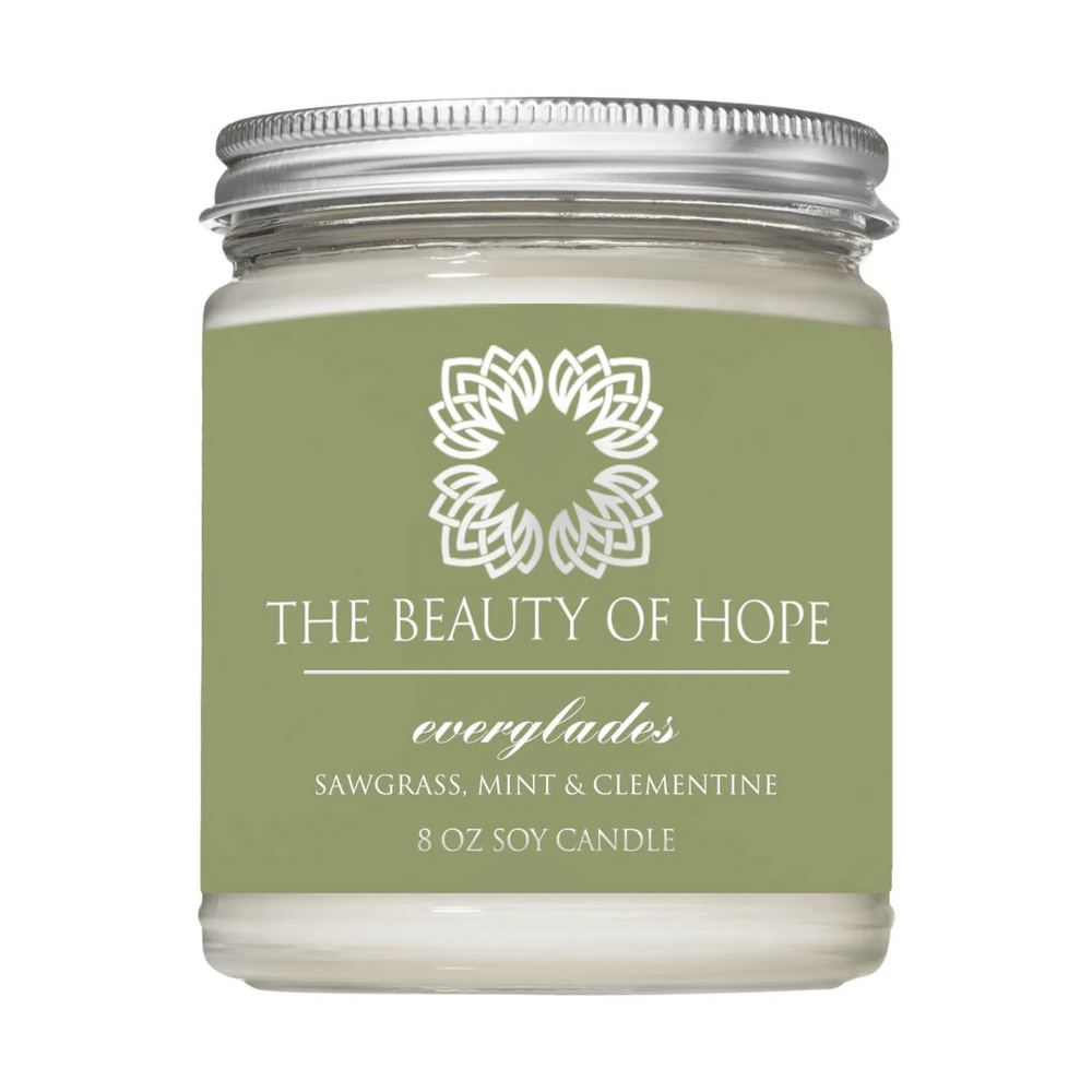 Everglades 8oz Candle | The Beauty of Hope in a clear glass jar with a metal lid, featuring a green label highlighting scents of sawgrass, mint, and clementine for wellness and relaxation.