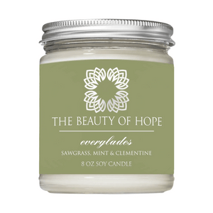 Everglades 8oz Candle | The Beauty of Hope in a clear glass jar with a metal lid, featuring a green label highlighting scents of sawgrass, mint, and clementine for wellness and relaxation.