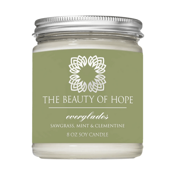 Everglades 8oz Candle | The Beauty of Hope in a clear glass jar with a metal lid, featuring a green label highlighting scents of sawgrass, mint, and clementine for wellness and relaxation.