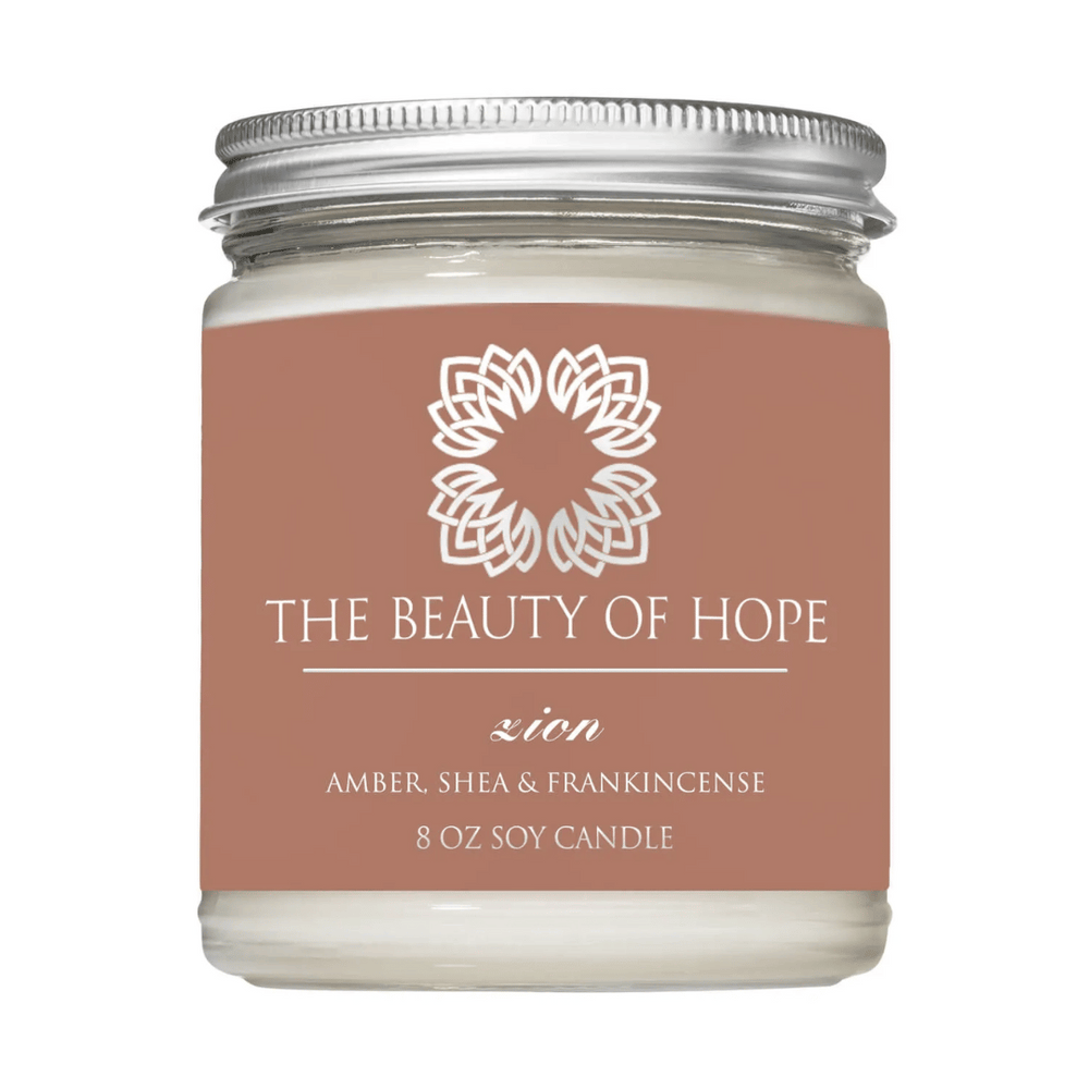 Zion 8oz Candle | The Beauty of Hope in a clear glass jar with a silver lid, featuring amber, shea, and frankincense scent for wellness and relaxation.