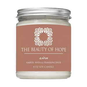 Zion 8oz Candle | The Beauty of Hope in a clear glass jar with a silver lid, featuring amber, shea, and frankincense scent for wellness and relaxation.