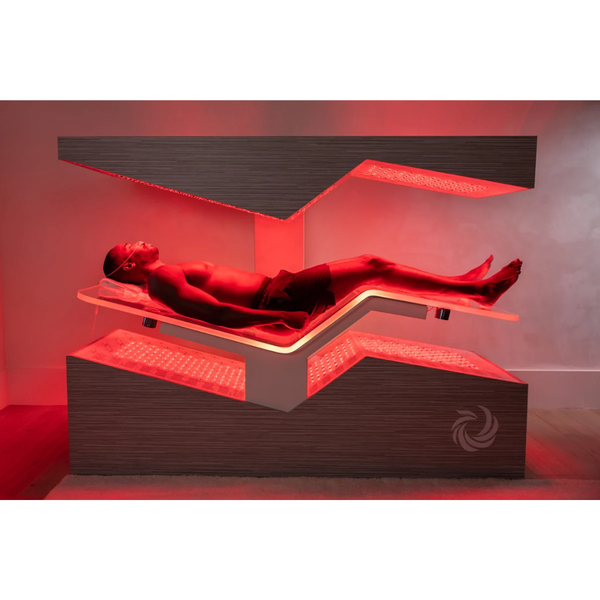 Man relaxing inside a futuristic wellness device emitting red light therapy, designed for body care and recovery, identified as Ammortal Chamber | Ammortal.