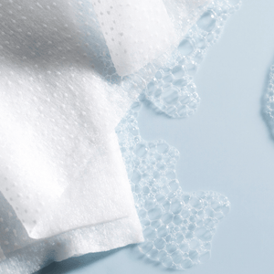 Close-up view of textured cleansing towelettes with foam bubbles on a light blue surface, highlighting Clean Slate Textured Cleansing Towelettes | Barefoot Scientist for skincare.