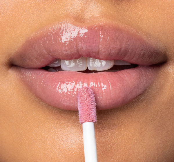Close-up of lips with a soft pink gloss being applied using a wand, showcasing the shine and delicate tint of Vitamin Glaze® Oil Infused Lip Gloss – Delicate Rose | Farmhouse Fresh.