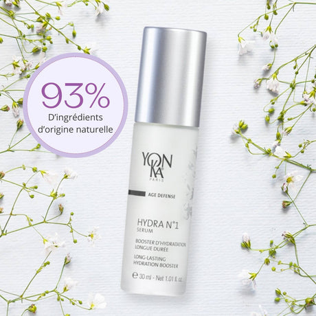 Hydra No. 1 Serum Hydrating | Yon-Ka Paris in a frosted bottle with silver cap, displayed on a white surface with delicate small white flowers, promoting long-lasting hydration.