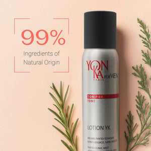 Bottle of Men’s Lotion YK - Phyto-Tonic Aftershave I Yon-Ka Paris with text highlighting 99% ingredients of natural origin, displayed alongside green botanical leaves on a light background.