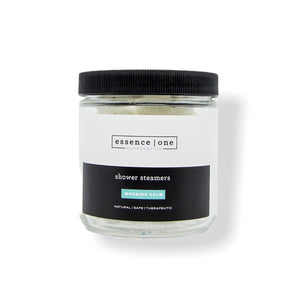 Glass jar with black lid containing shower steamers branded as Shower Steamer | Essence One, promoting natural, safe, and therapeutic body care for a calming wellness experience.