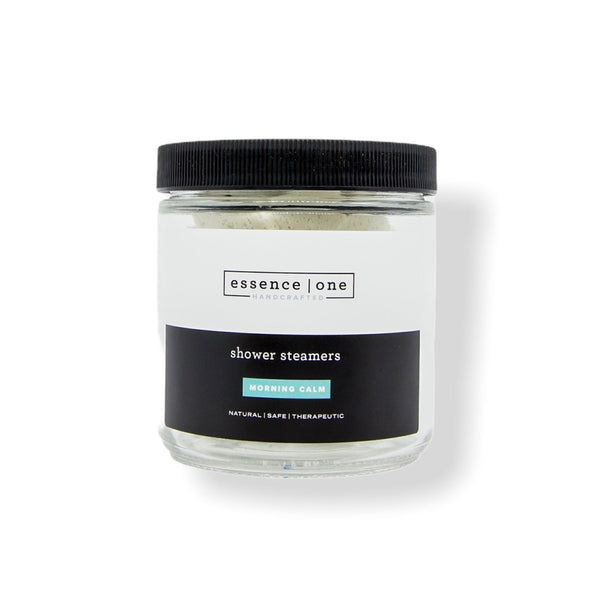Glass jar with black lid containing shower steamers branded as Shower Steamer | Essence One, promoting natural, safe, and therapeutic body care for a calming wellness experience.