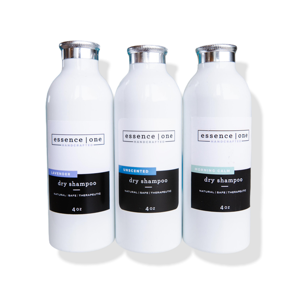 Three white bottles of Dry Shampoo | Essence One in lavender, unscented, and morning calm variants with silver caps, promoting a natural, safe, and therapeutic hair care solution.