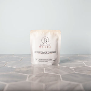 Luxe Bath Ritual Kit | Live Love Spa featuring Bathorium Crush Ancient Oat Hydration bath soak in minimalist packaging on a tiled surface, promoting skincare and wellness.