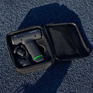 Compact black massage device with three interchangeable heads neatly stored in an open black carrying case on a textured blue surface labeled Hypervolt Go 3 | Hyperice.