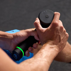 Person holding and using the Hypervolt 3 Pro | Hyperice percussion massage device with a glowing green indicator light for muscle recovery and wellness.