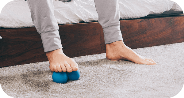 Person using blue massage tool on foot while seated, demonstrating recovery and wellness with RAD Roller Original | RAD for body care and muscle relief.