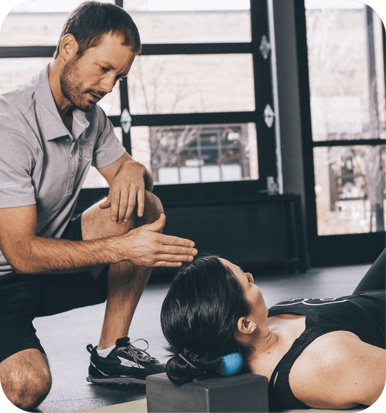 Man demonstrating use of RAD Roller Stiff | RAD as a recovery tool by applying it to a woman's neck for muscle relief in a wellness setting.