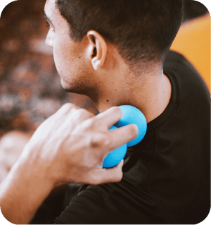 Person using a blue RAD Roller Stiff | RAD massage tool on the back of their neck for muscle relief and recovery in a wellness setting.