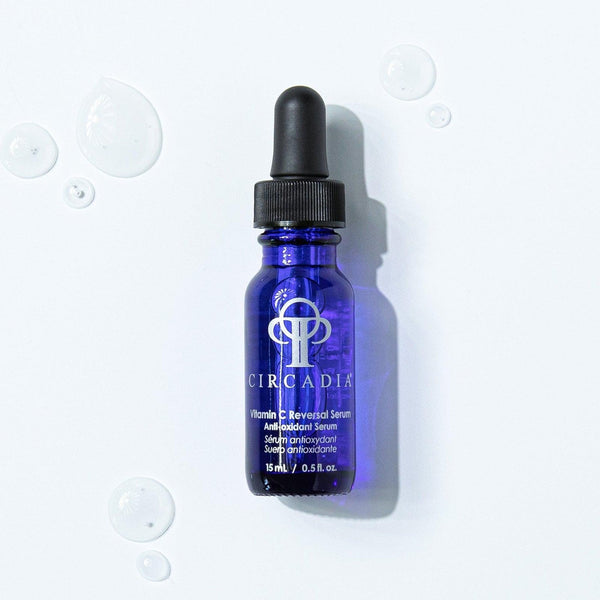 Blue glass dropper bottle of Vitamin C Reversal Serum (Professional) | Circadia with clear serum droplets on a white background for skincare use.