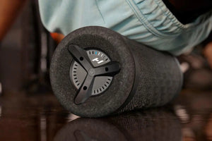 Close-up of a black textured foam roller with control dial resting on a reflective surface, part of the Vyper 3 | Hyperice recovery tools for body care and wellness.